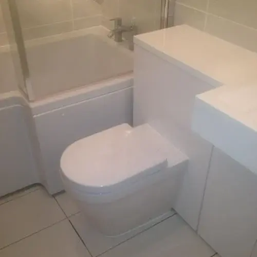 Fitted white toilet with concealed cistern in a tiled bathroom