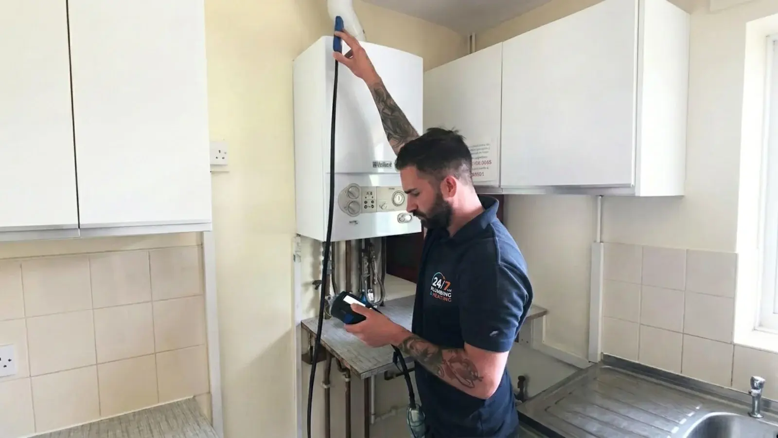 Plumbing engineer checking a wall mounted boiler in a kitchen