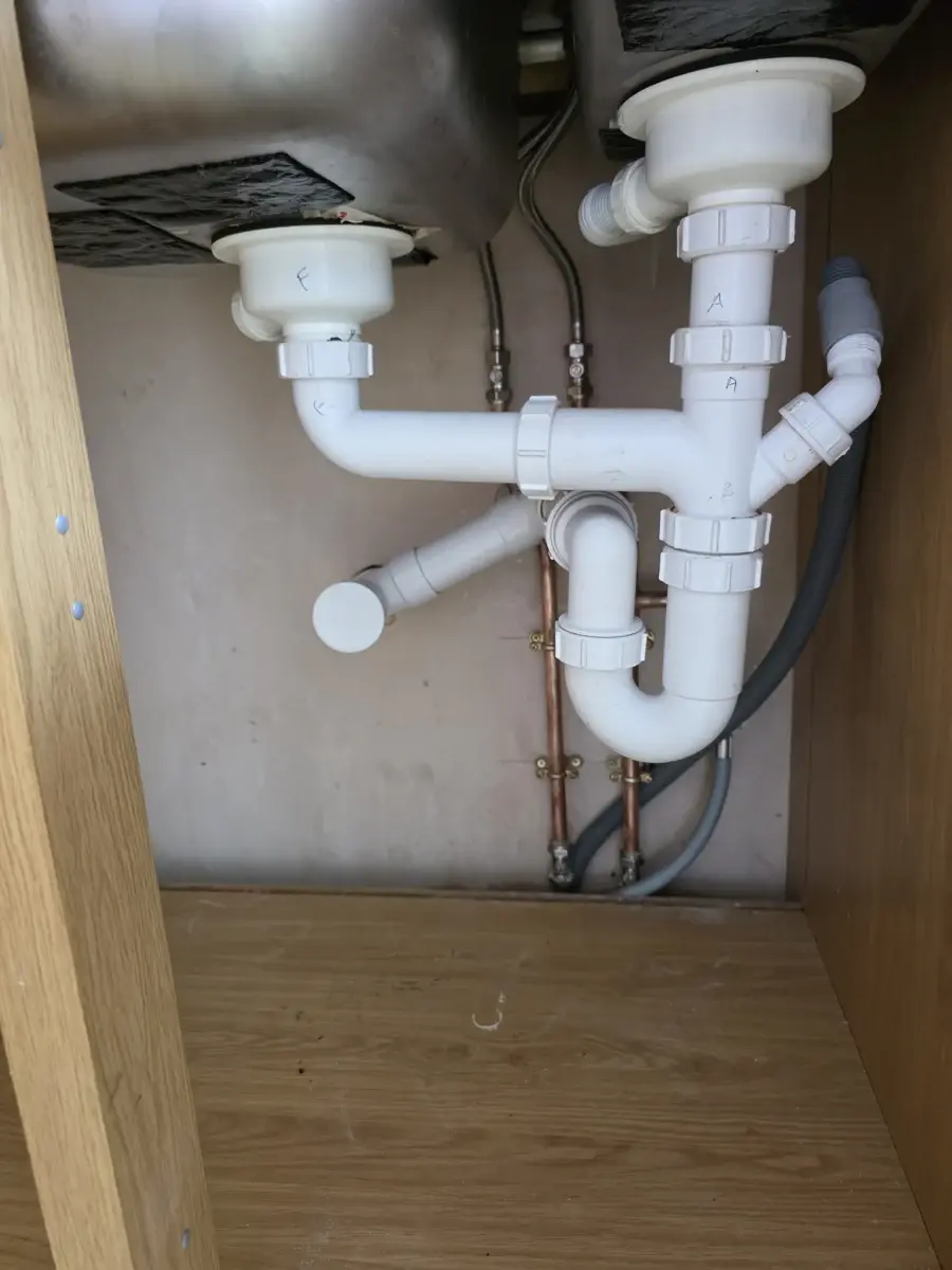 Replaced waste pipes and trap beneath a kitchen sink