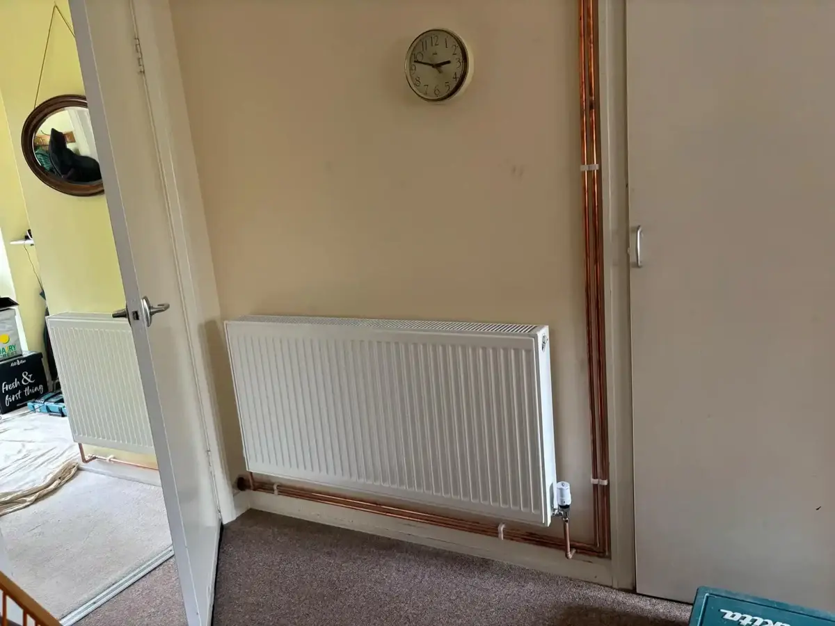 White panel radiators connected to exposed copper heating pipework