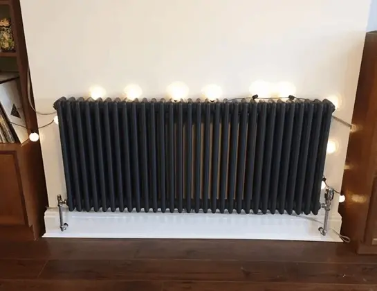 Installed black column radiator with connected valves
